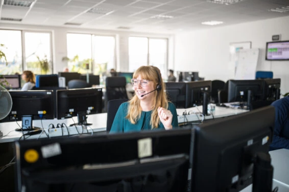 Smiling businesswoman by computers in office