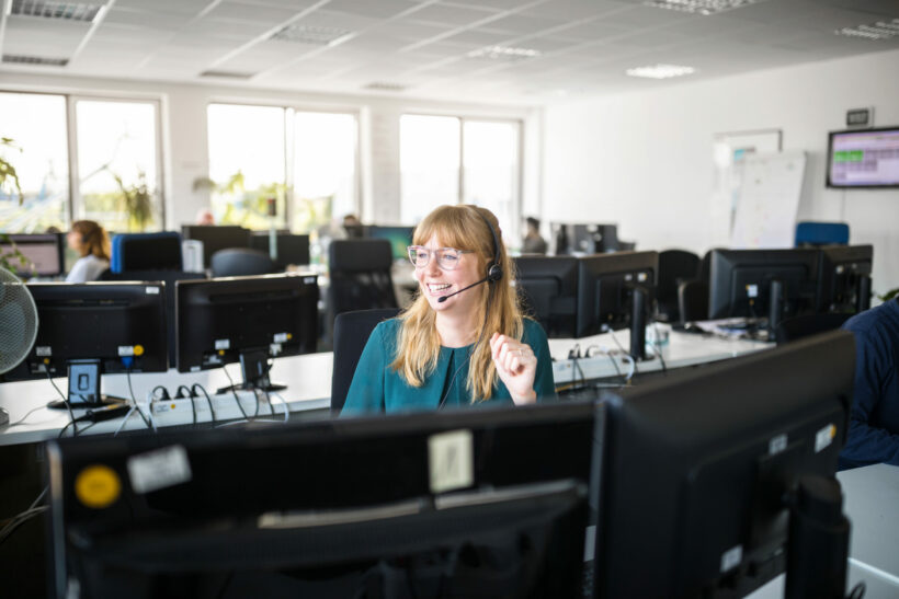 Smiling businesswoman by computers in office