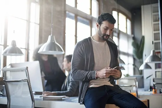 Businessman checking the mobile phone sitting on his desk