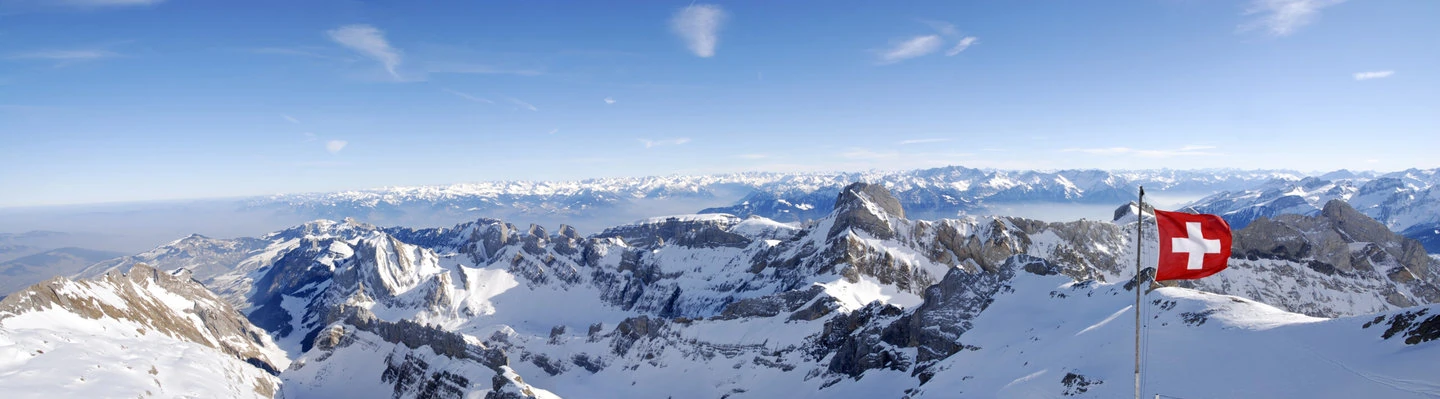 Swiss flag in the wind over panoramic mountain view (xxl)
