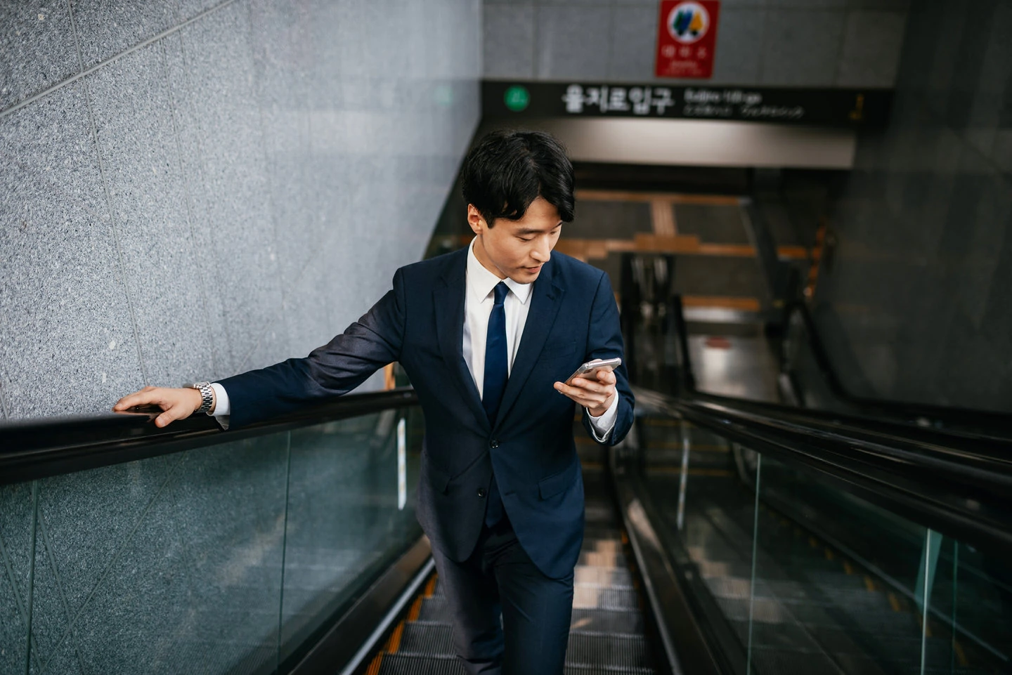 Korean businessman using smart phone while commuting