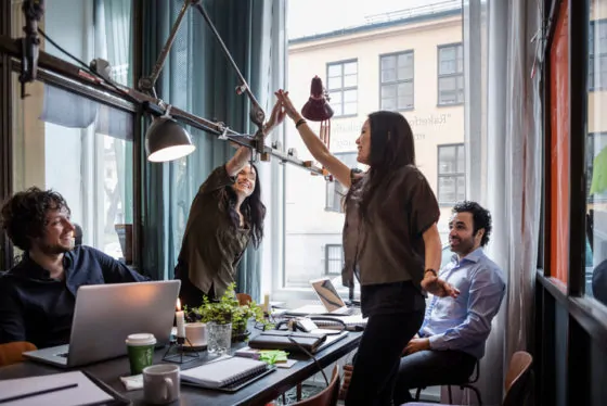 Female colleagues giving high-five while standing at table in meeting