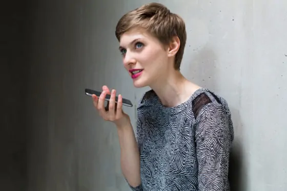 Woman using cell phone at concrete wall