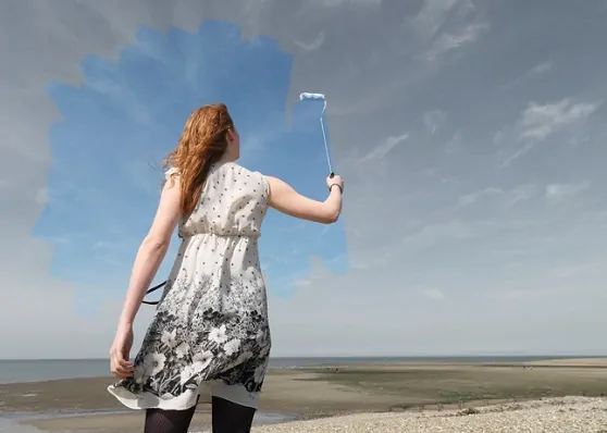 Young woman painting grey sky blue
