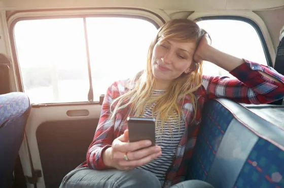 Woman sitting in back of car using mobile phone.