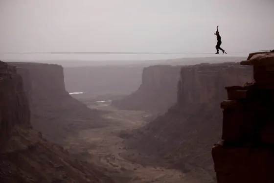 Andy lewis working on a world record highline, three hundred and forty feet long, at the fruit bowl in moab, utah, usa.